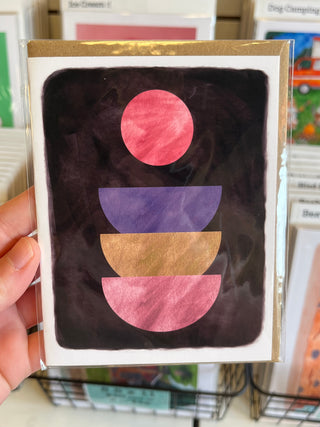 Card with geometric shapes held by a hand in a store setting