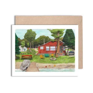 Greeting card with a red cabin by a lake, surrounded by trees and a dock.